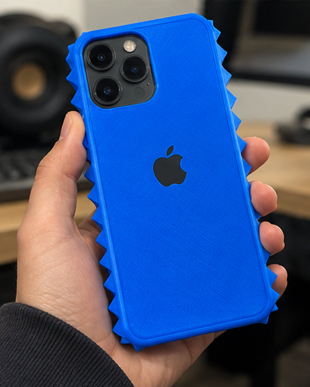 Prickly Phone Case in electric blue, held in a hand to show size and side spikes